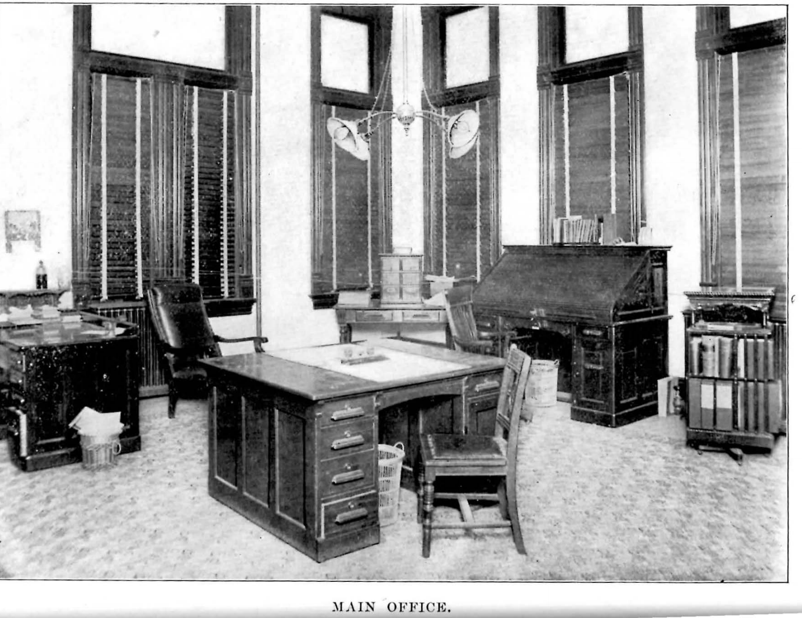 An image of a CWU office with desks from the 1900-01 CWU Catalogue. There are three desks in the room and several windows.